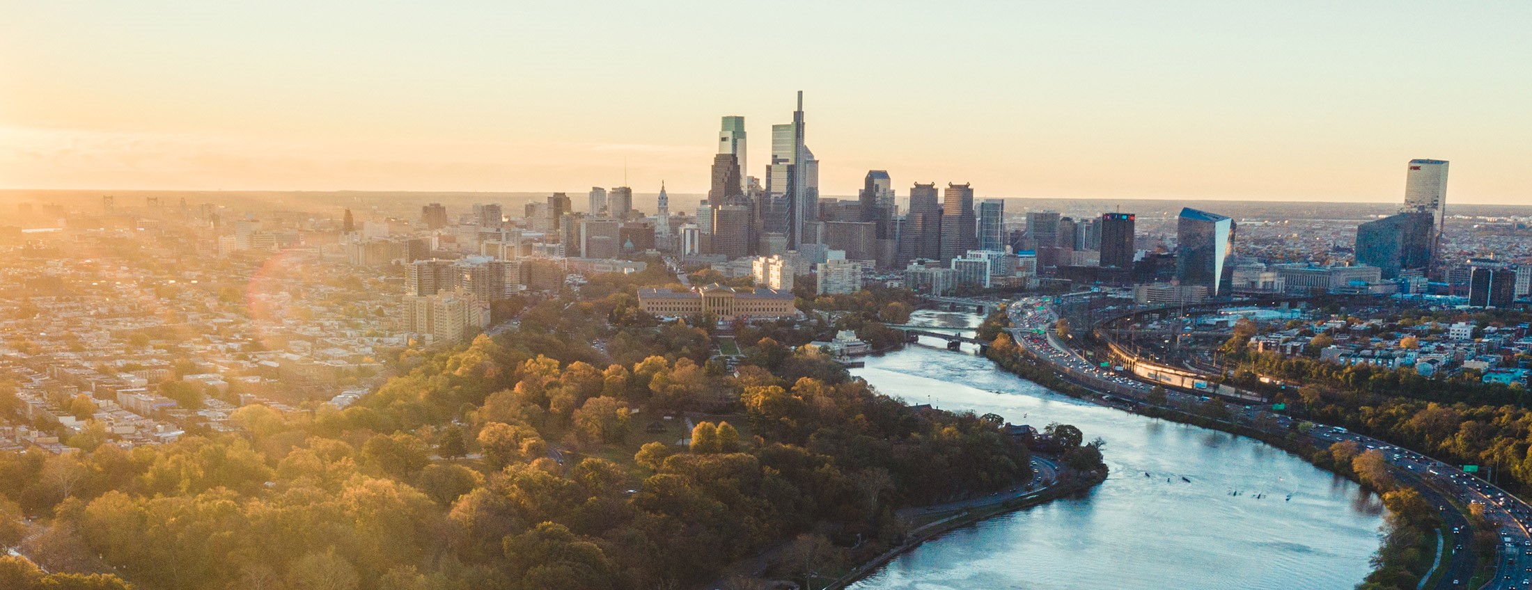 https://www.visitphilly.com/wp-content/uploads/2019/12/philadelphia-skyline-aerial-sunrise-elevated-angles-for-vp-2200x1237px.jpg